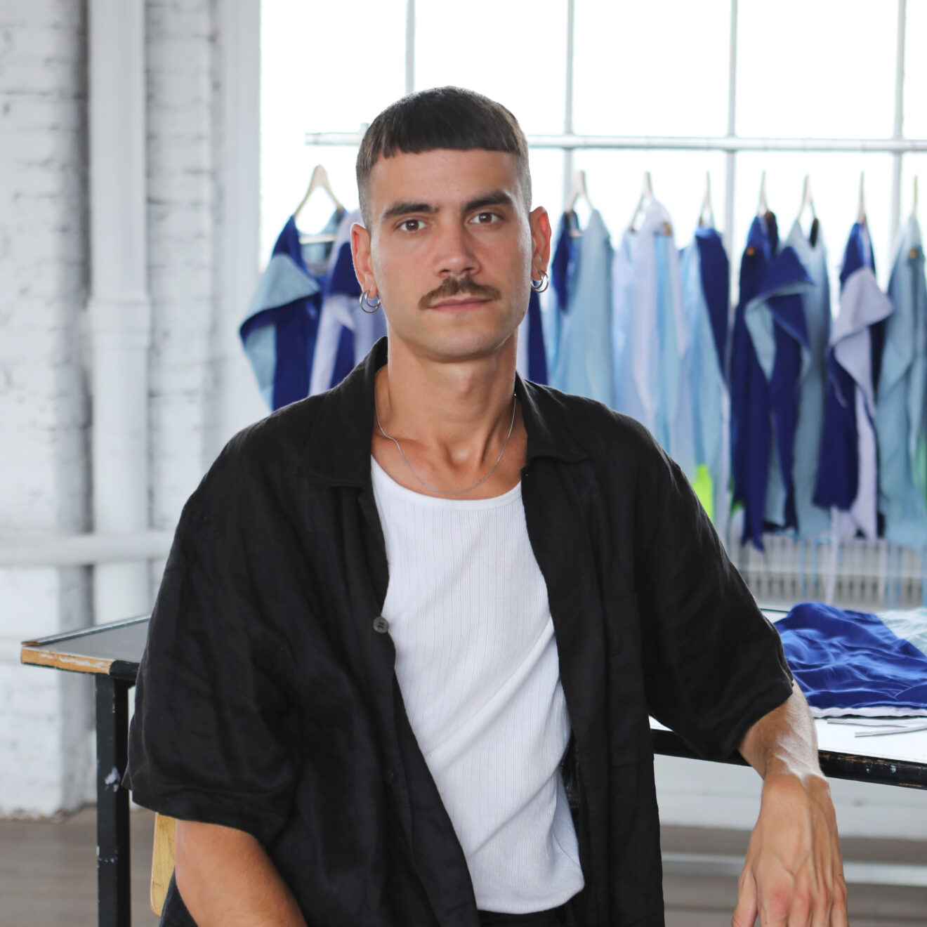 Portrait of Gabriel Fontana sitting in his studio before the team uniforms for Multiplay