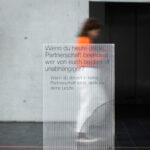 Transparent text wall with a woman walking behind it.